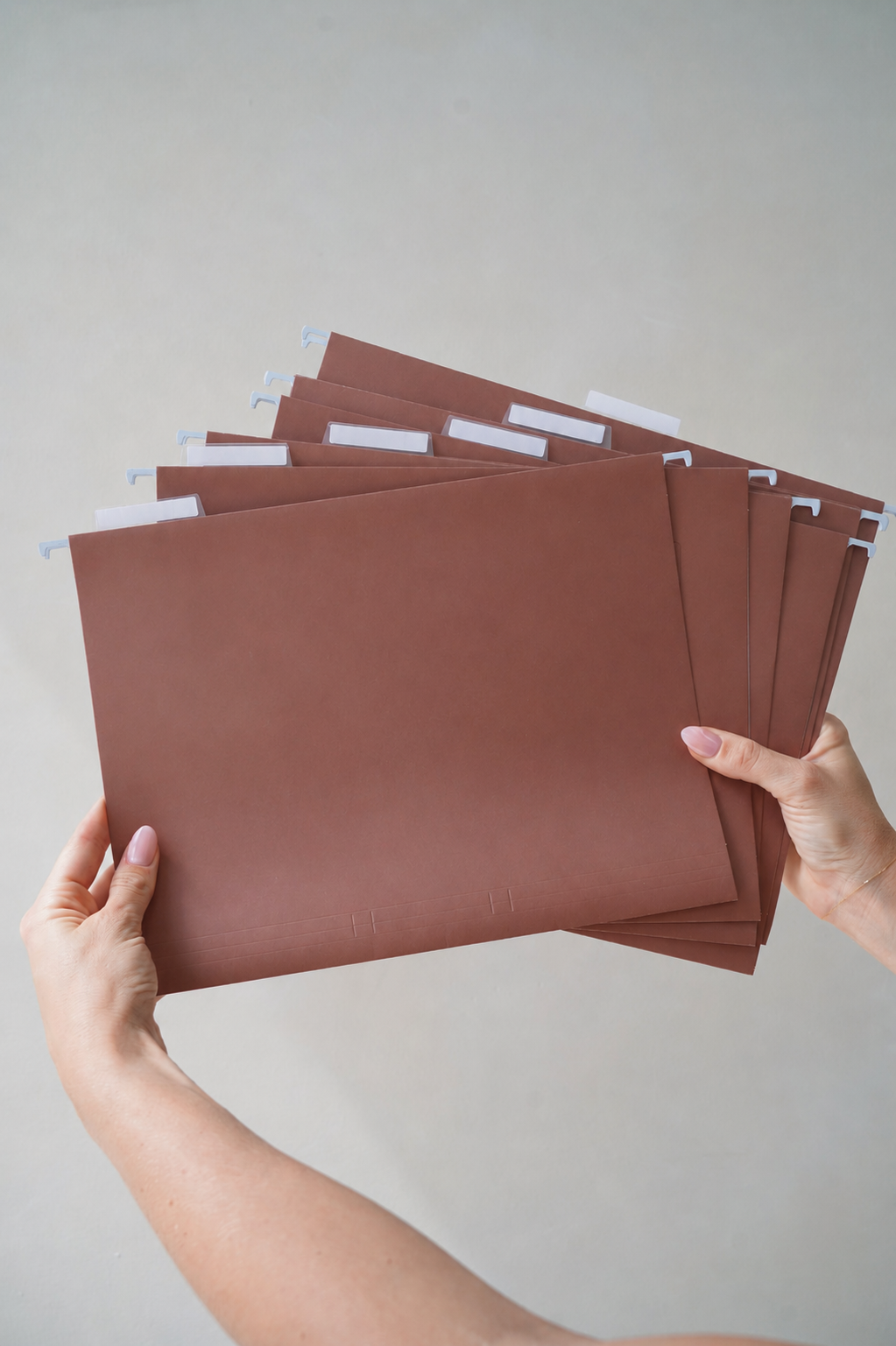 Hands holding a fanned stack of CUBBLI expansion files, front view