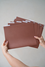 Hands holding a fanned stack of CUBBLI expansion files, front view