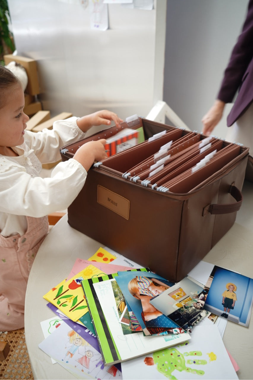 Toddler placing artwork and photos into an open CUBBLI Chocolate keepsake box