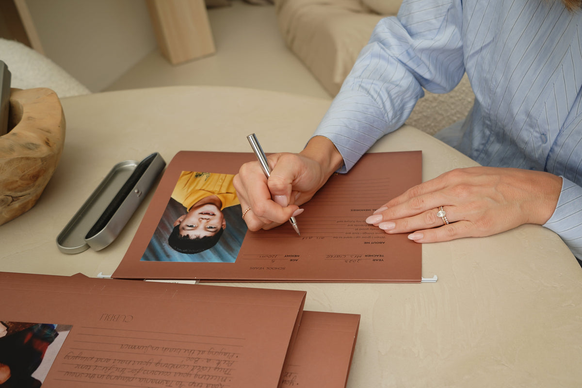Hand signing a child's photo card with the CUBBLI Heritage pen