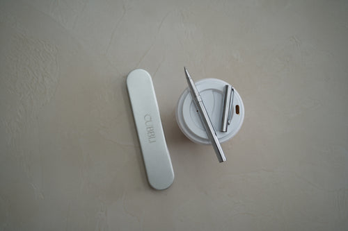 CUBBLI Heritage pen beside its cap and a small ink jar, on a stone surface