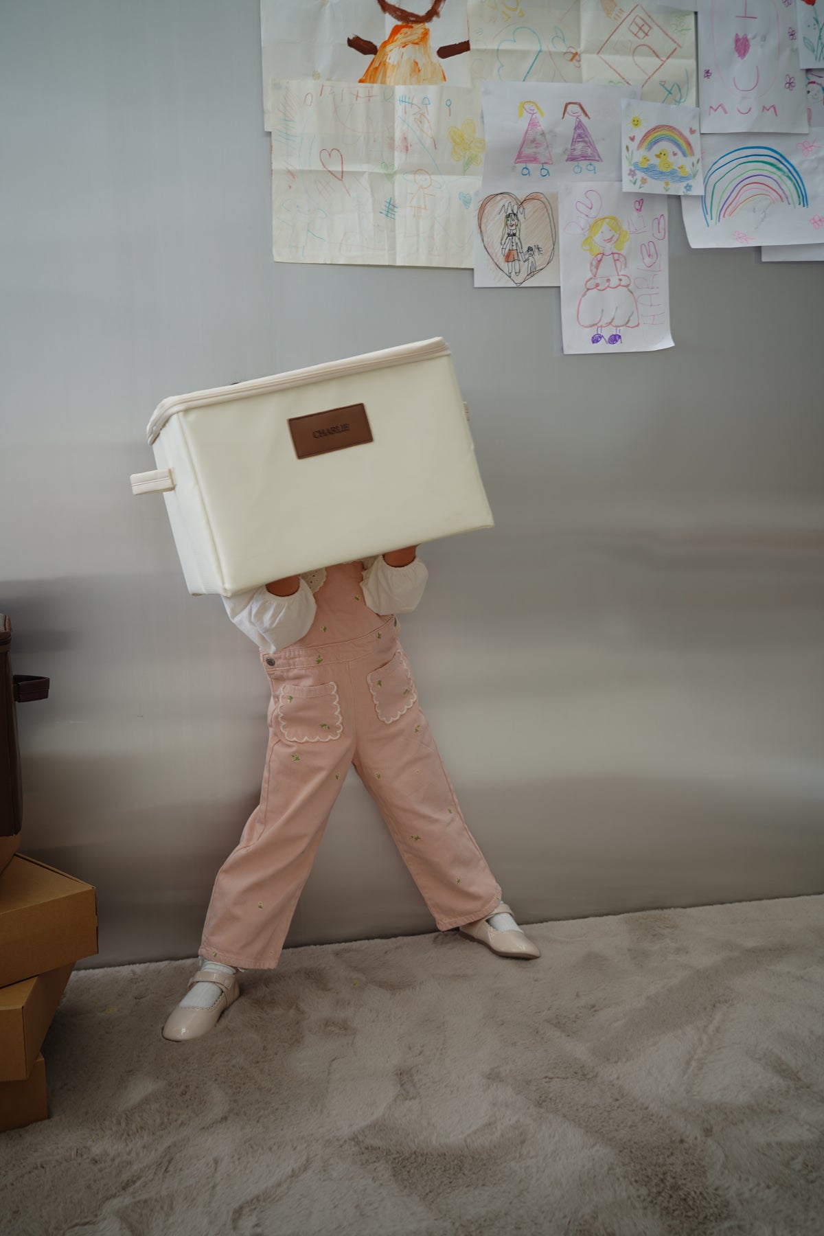 Child playfully carrying a CUBBLI Cream keepsake box overhead