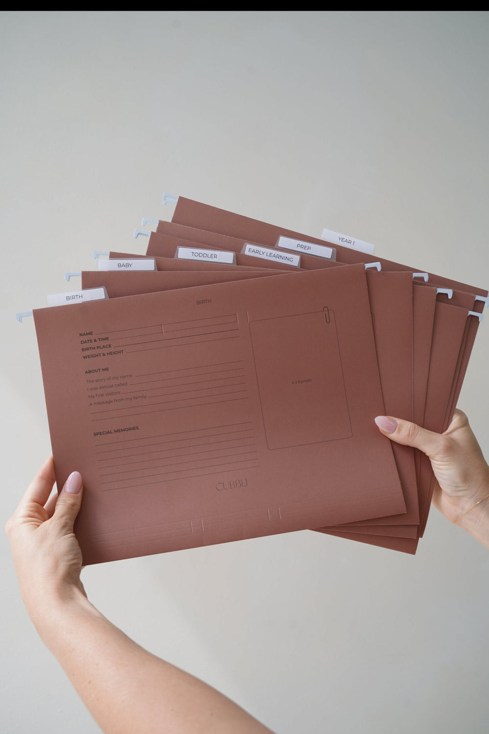 Hands holding a fanned stack of CUBBLI keepsake file folders